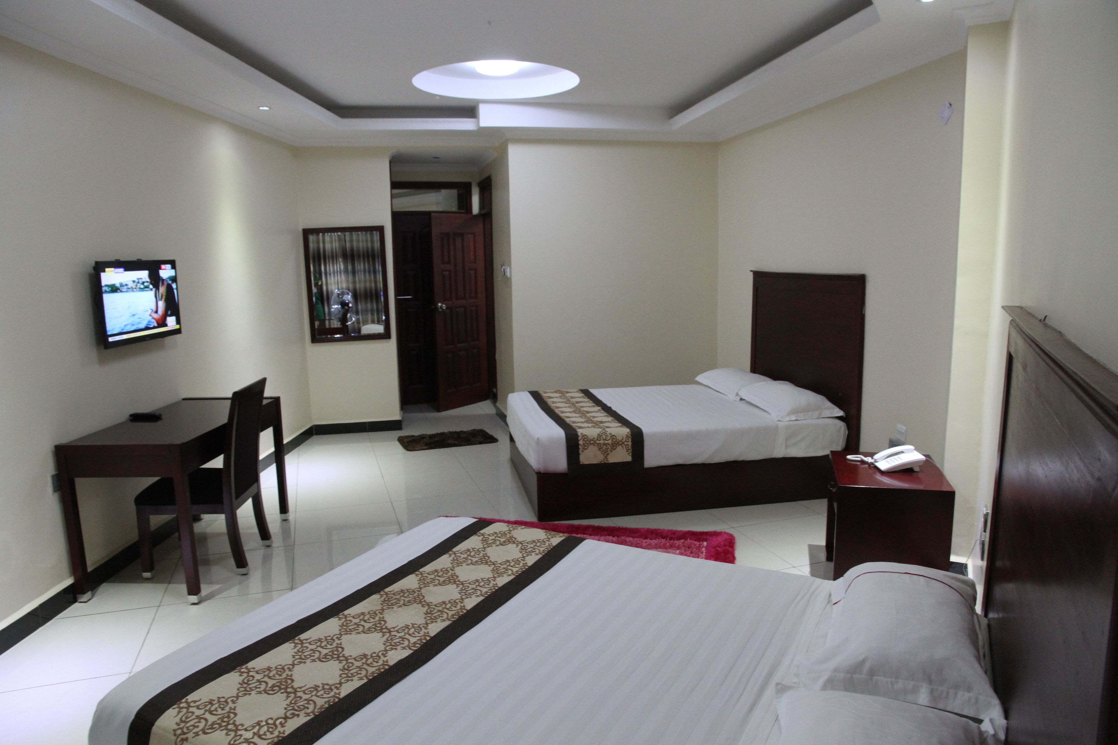 Une chambre d’hôtel avec deux lits, un bureau, une chaise, une télévision et un téléphone.