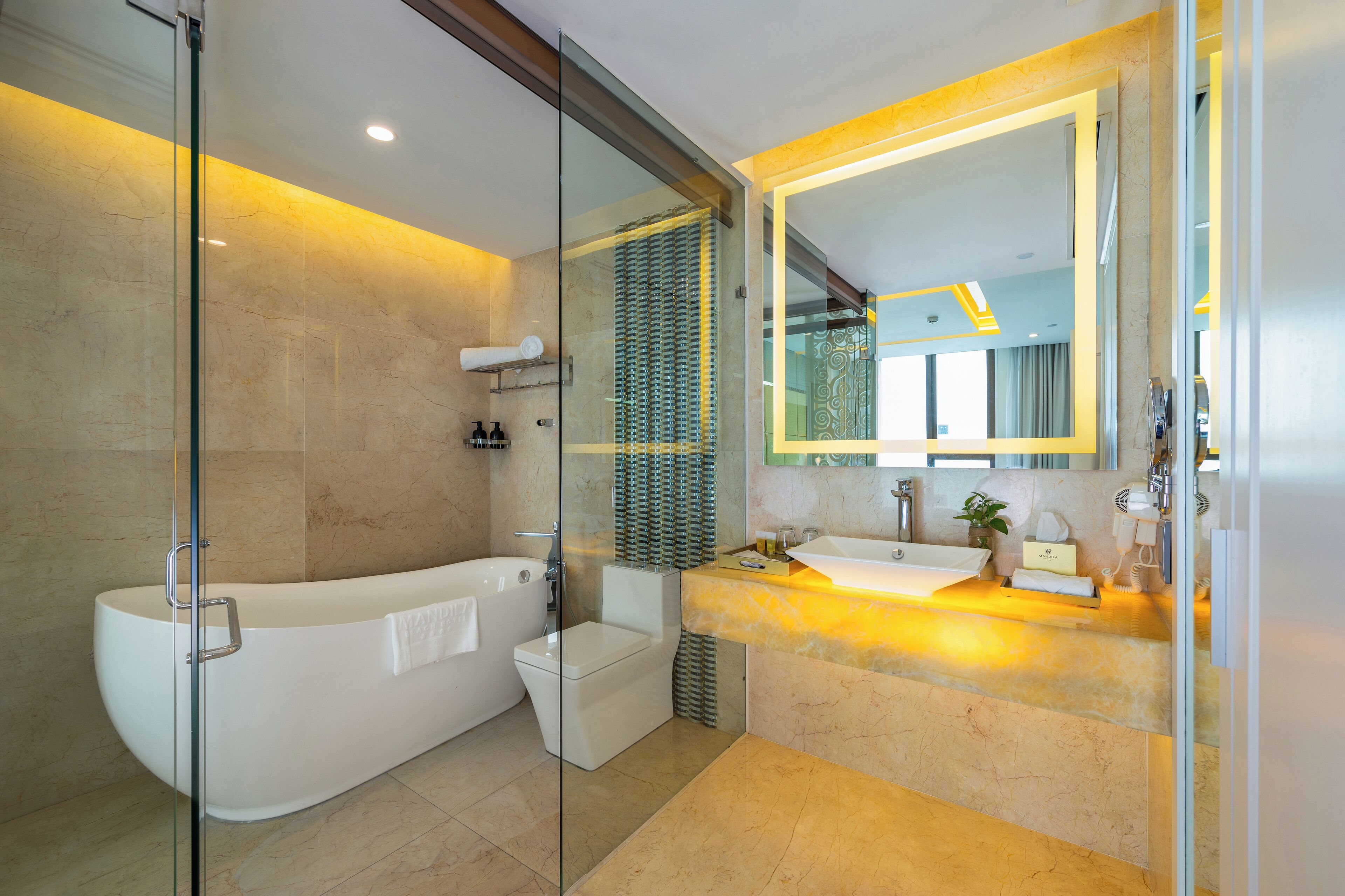 A modern bathroom with a glass-enclosed shower, a freestanding bathtub, a toilet, and a vanity with a mirror.