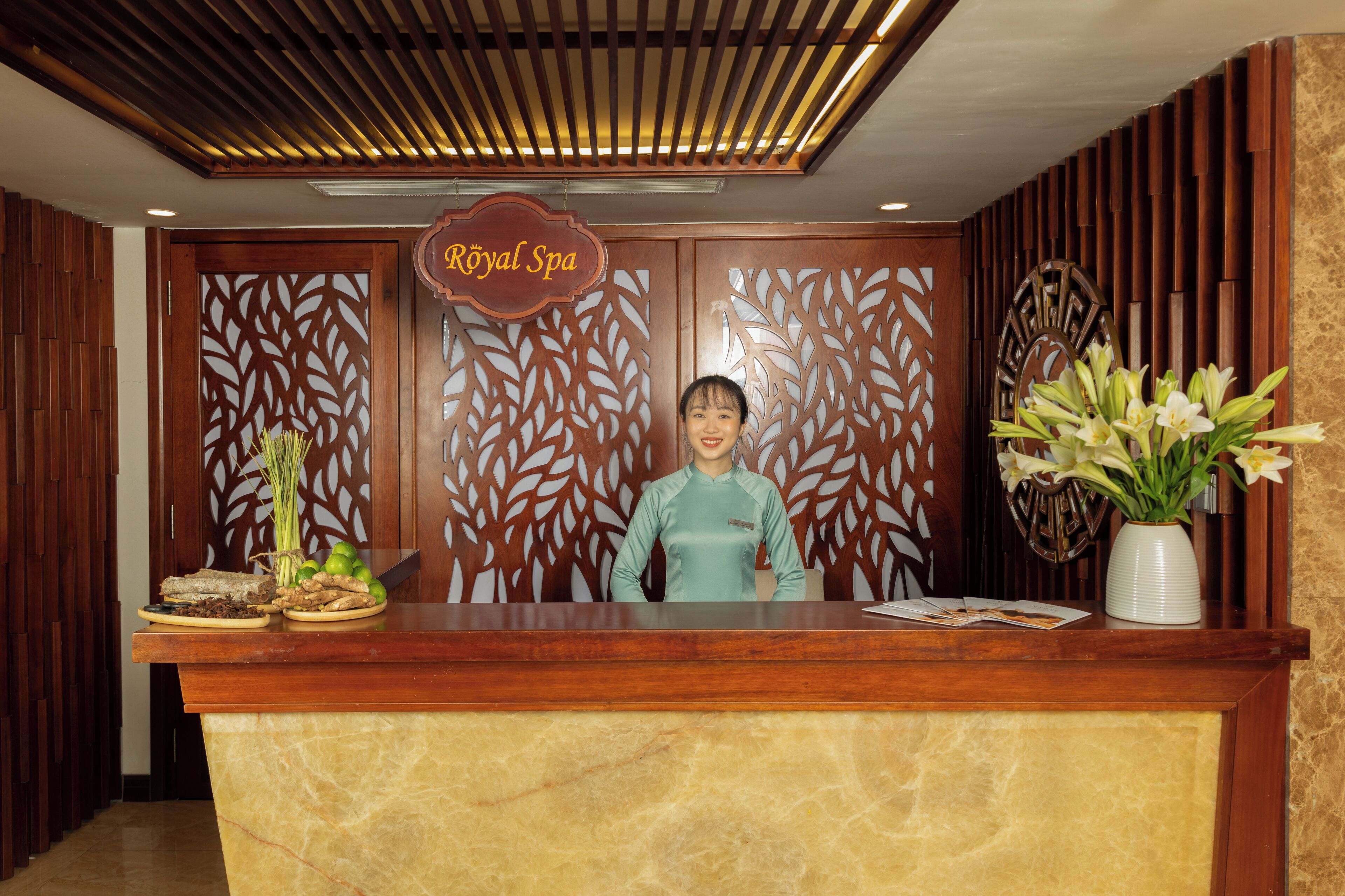 Una mesa de recepción con un cartel que dice "Royal Spa" y una recepcionista detrás.