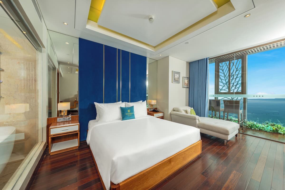 Een moderne hotelkamer met een groot bed, een zithoek en uitzicht op de oceaan.