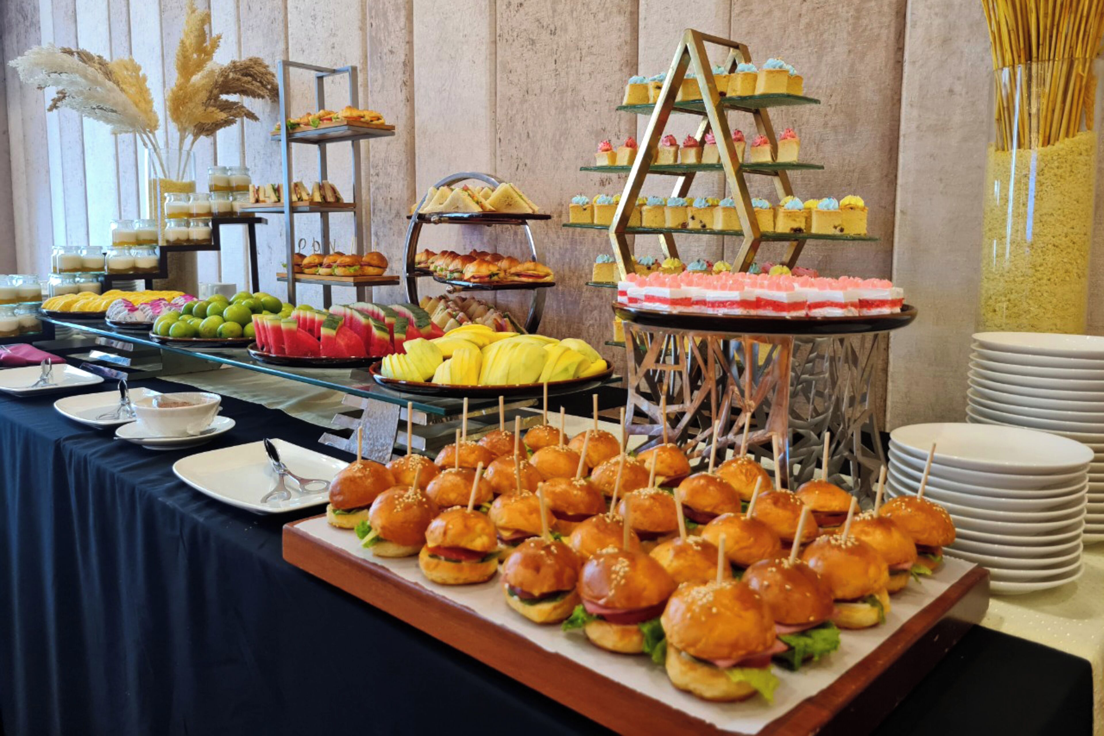 A buffet with various food items including sandwiches, desserts, and fruit.