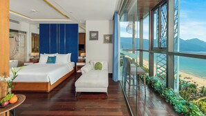 Une chambre d’hôtel moderne avec un grand lit, un canapé et un balcon offrant une vue sur la plage.