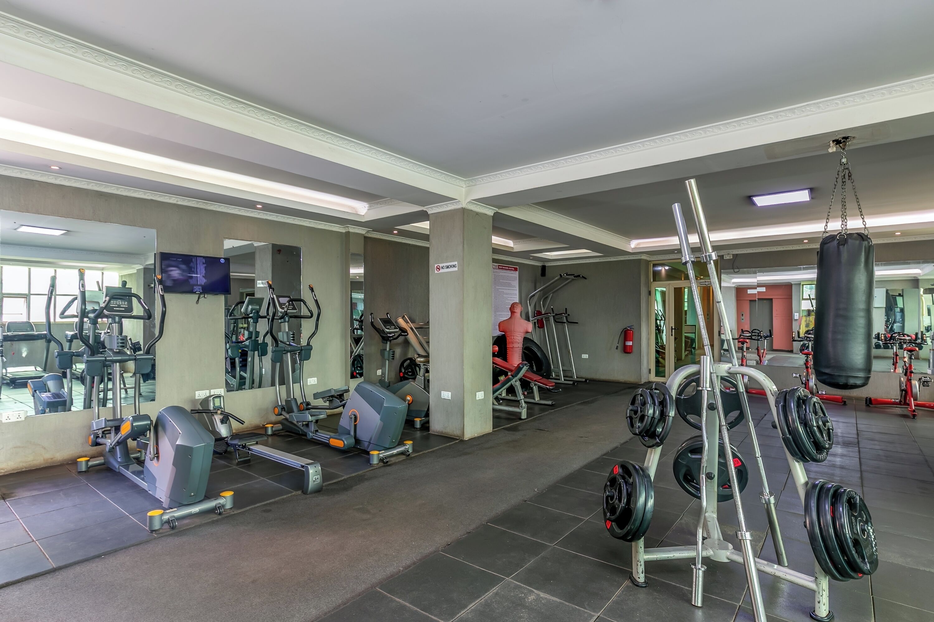 A gym with various exercise equipment, including treadmills, weight machines, and a punching bag.