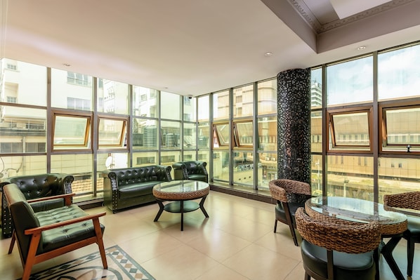 A spacious room with large windows, leather sofas, and a glass table.