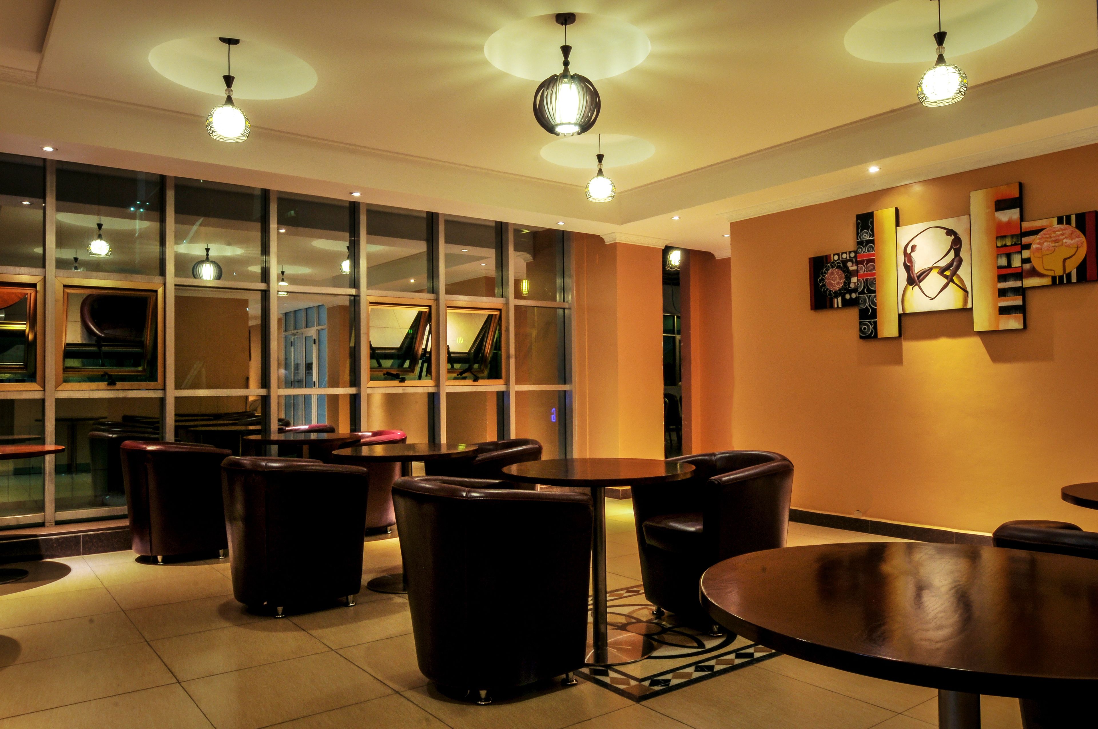 A modern interior with round tables and leather chairs, large windows, and contemporary wall art.