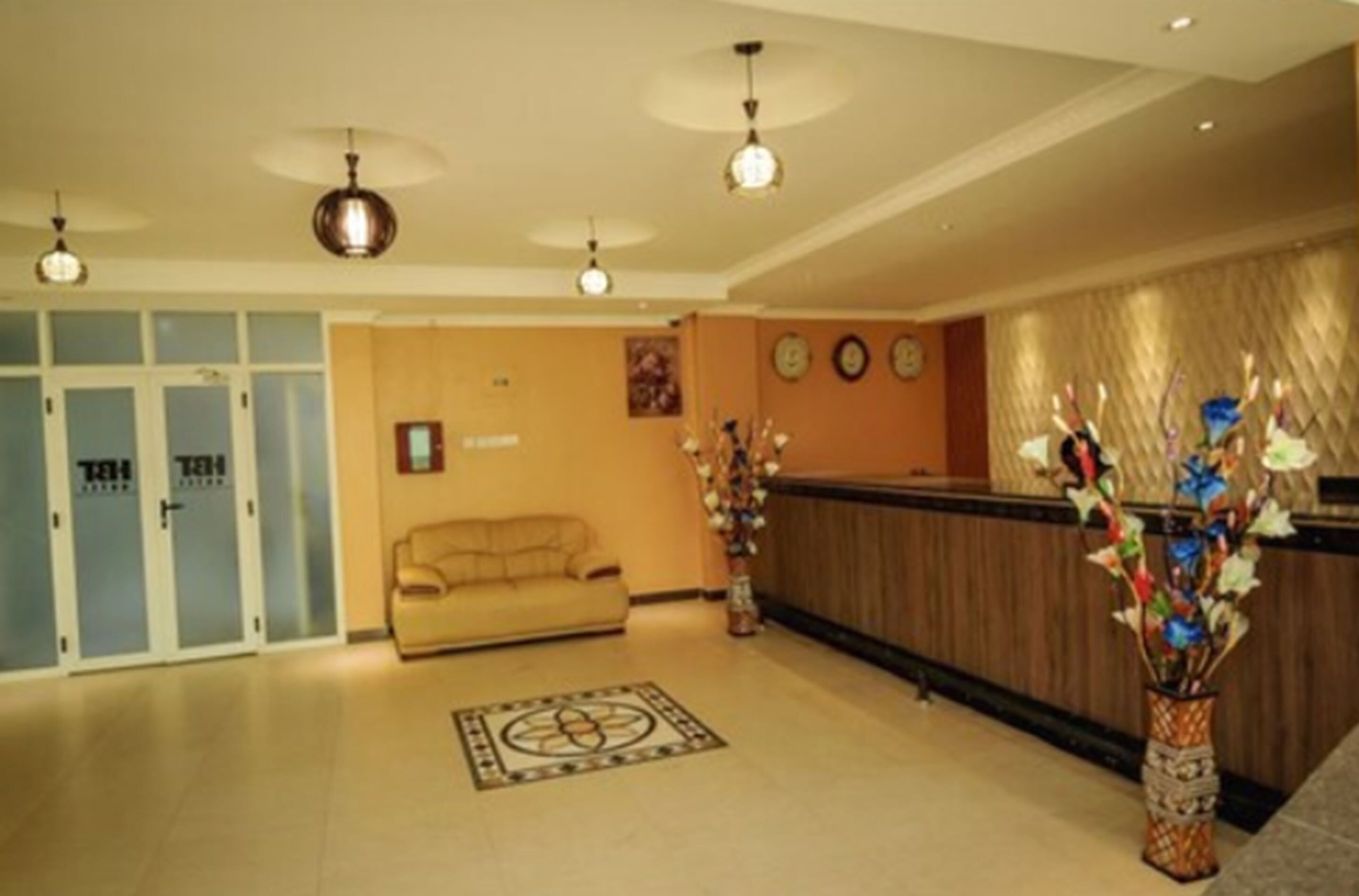 Eine Hotellobby mit einer Rezeption, einer Couch, einem gemusterten Teppich und einer dekorativen Vase.