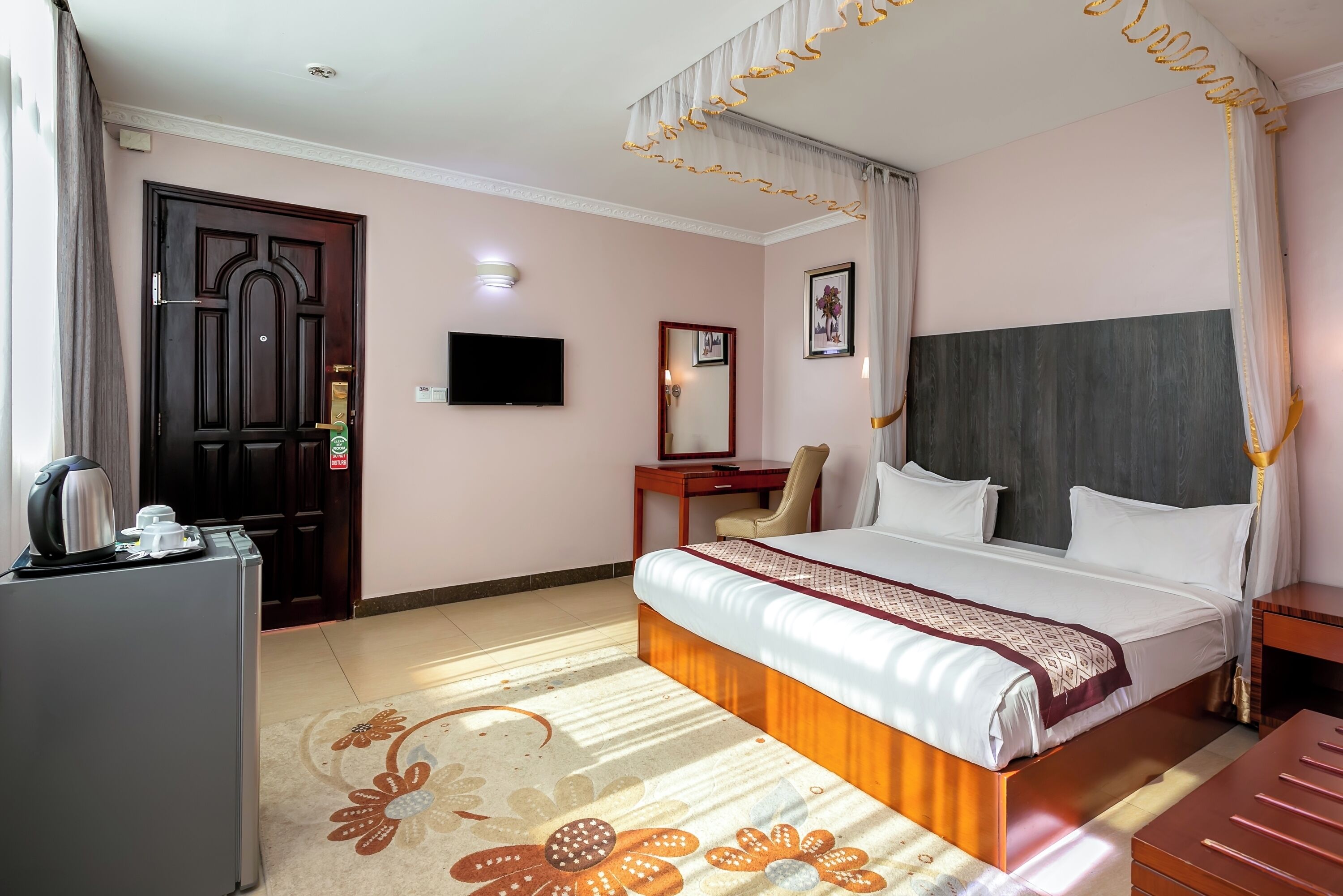 A hotel room with a bed, a desk, a chair, a television, and a wardrobe.