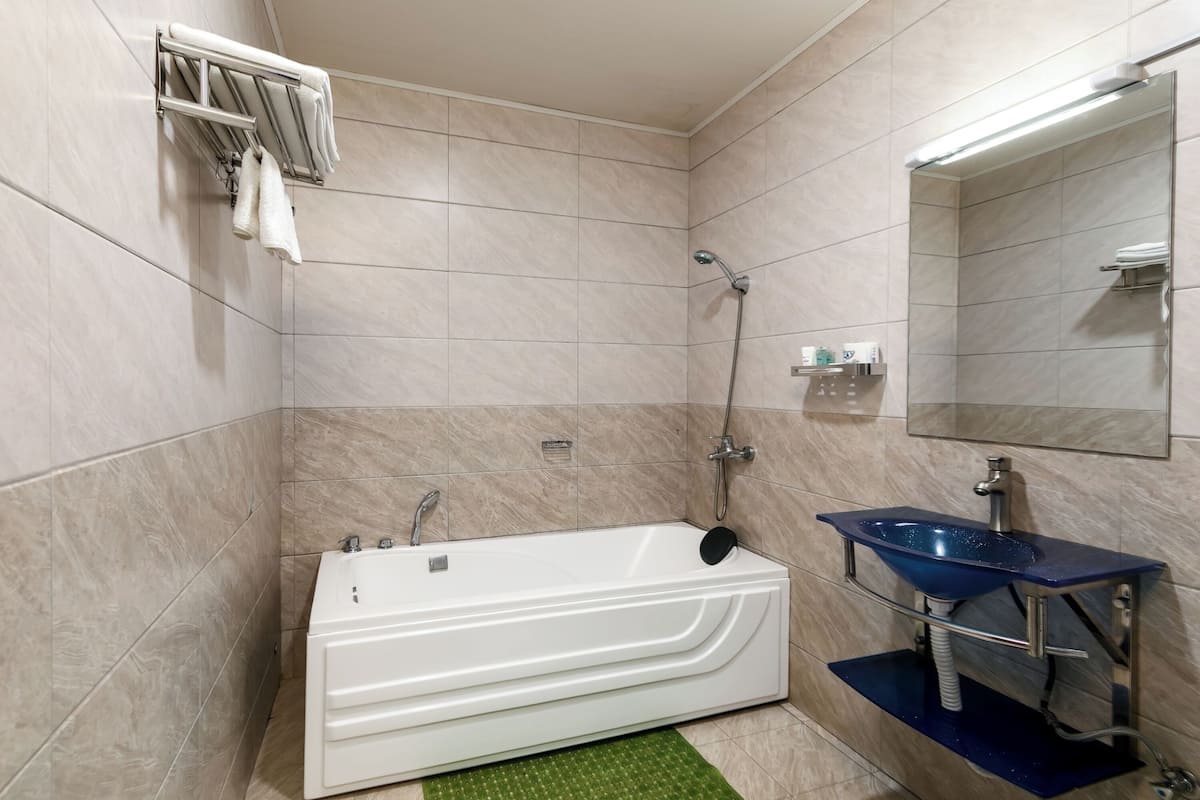 Un baño moderno con una bañera blanca, un lavabo azul y un espejo grande.
