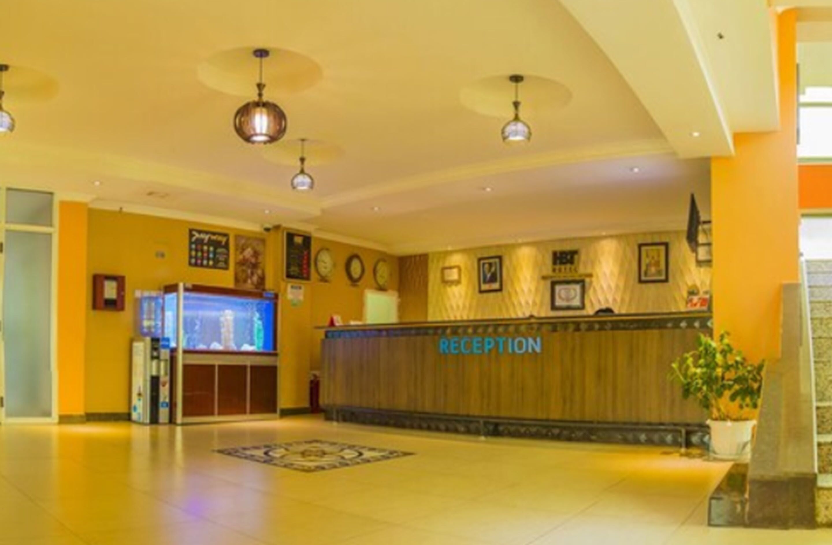 A reception area with a wooden reception desk labeled "RECEPTION," a fish tank, and a clock on the wall.