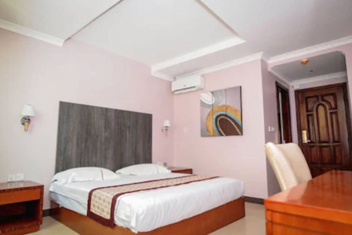 Una habitación de hotel con una cama, mesitas de noche, un escritorio y una silla.