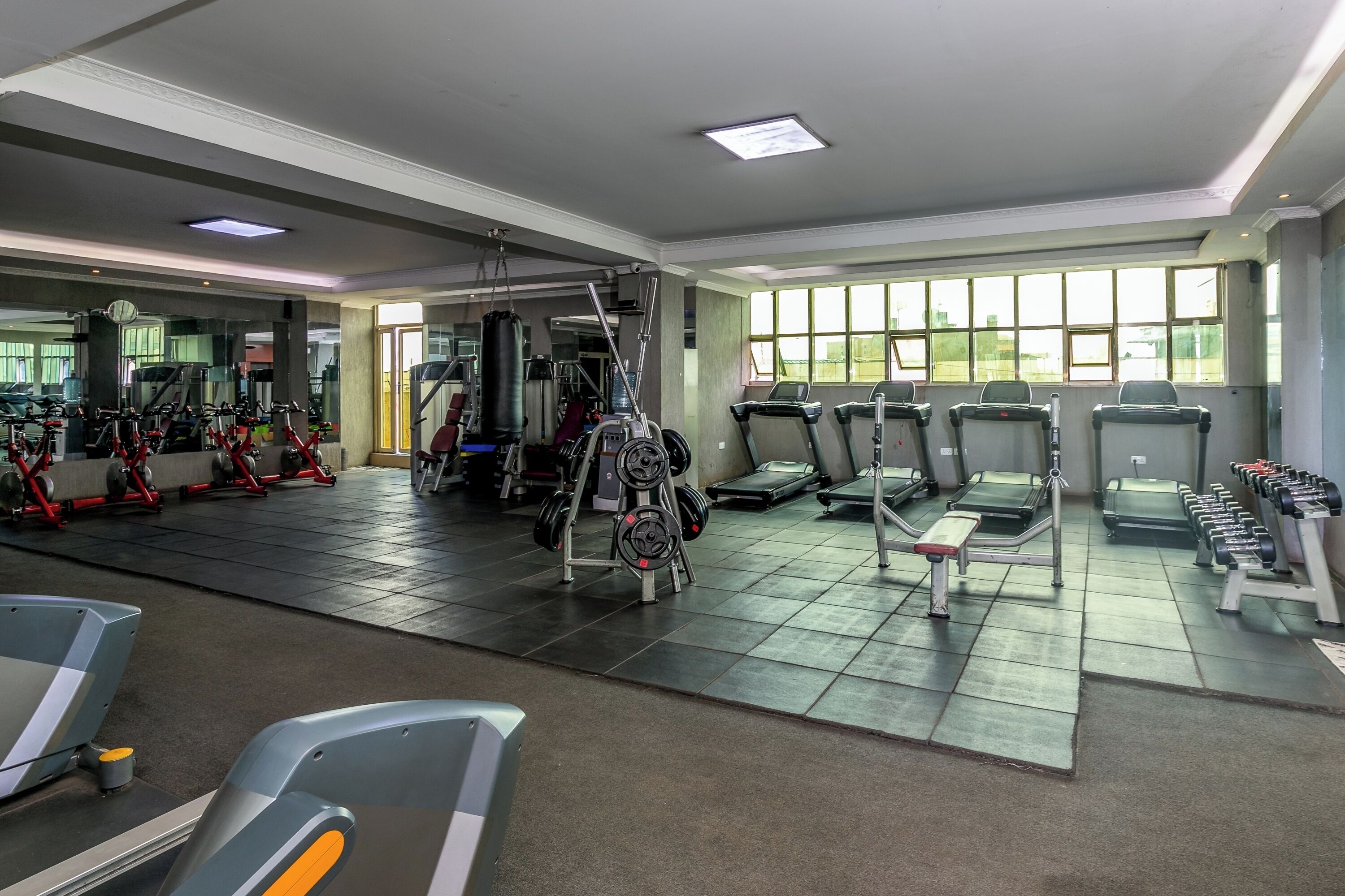 A gym with various exercise equipment, including treadmills, weight machines, and a punching bag.