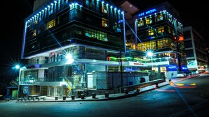 A multi-story hotel with illuminated signage, a visible entrance, and a parking area. - Russel Hotel (Kampala)