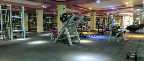 A gym with various exercise equipment, including treadmills, weight machines, and free weights.