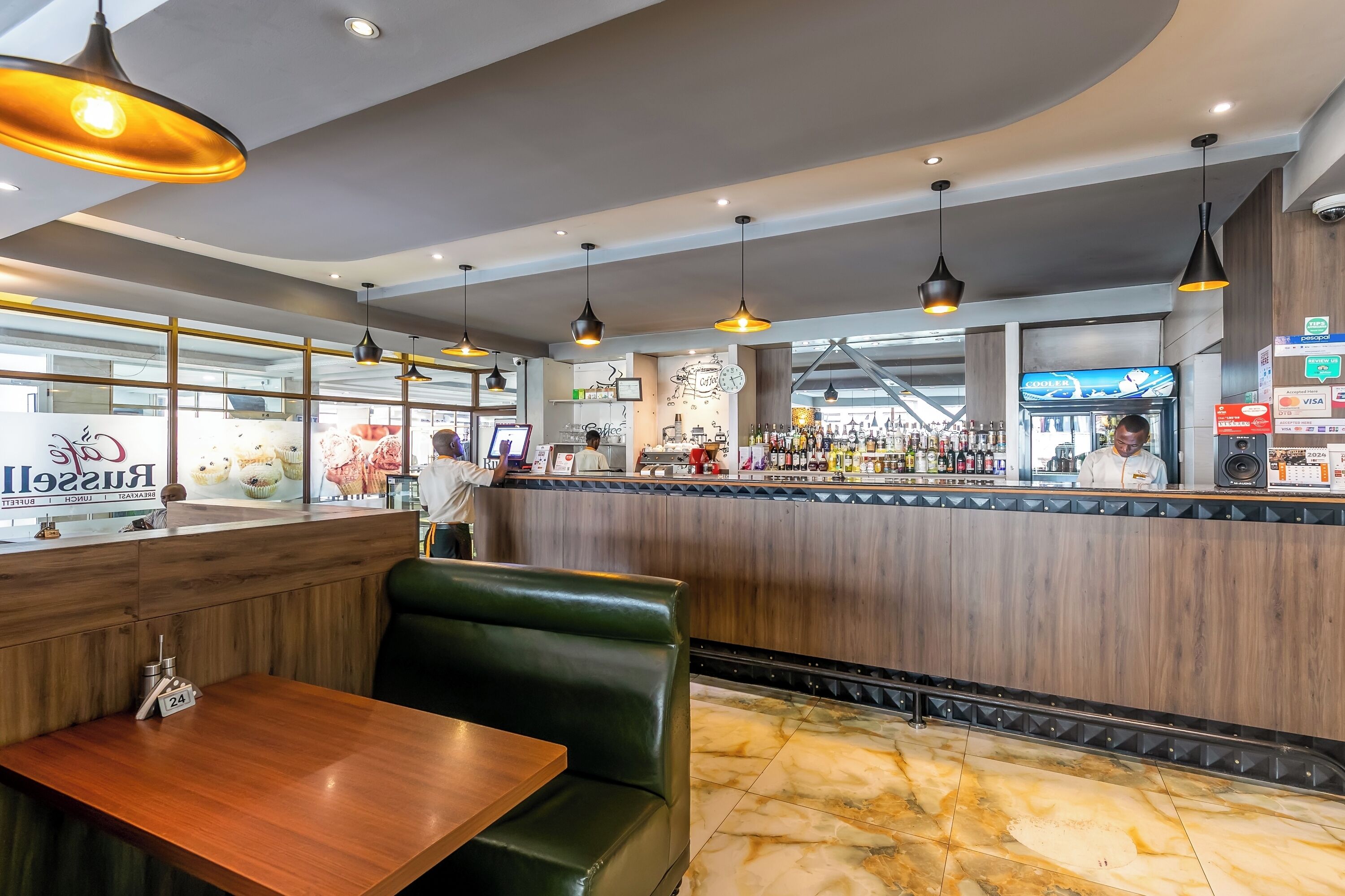 Un interior de restaurante con cabinas de madera, una zona de bar e iluminación colgante.
