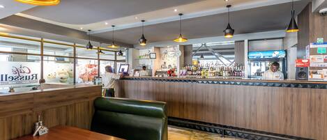 A restaurant interior with wooden booths, a bar area, and pendant lighting.