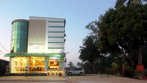 Ein Hotel mit moderner Fassade, einem grün-weißen Farbschema und einem sichtbaren Eingang, vor dem ein Auto geparkt ist.