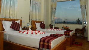 Ein Hotelzimmer mit zwei Betten, einer Essecke und Blick auf den Sonnenuntergang.