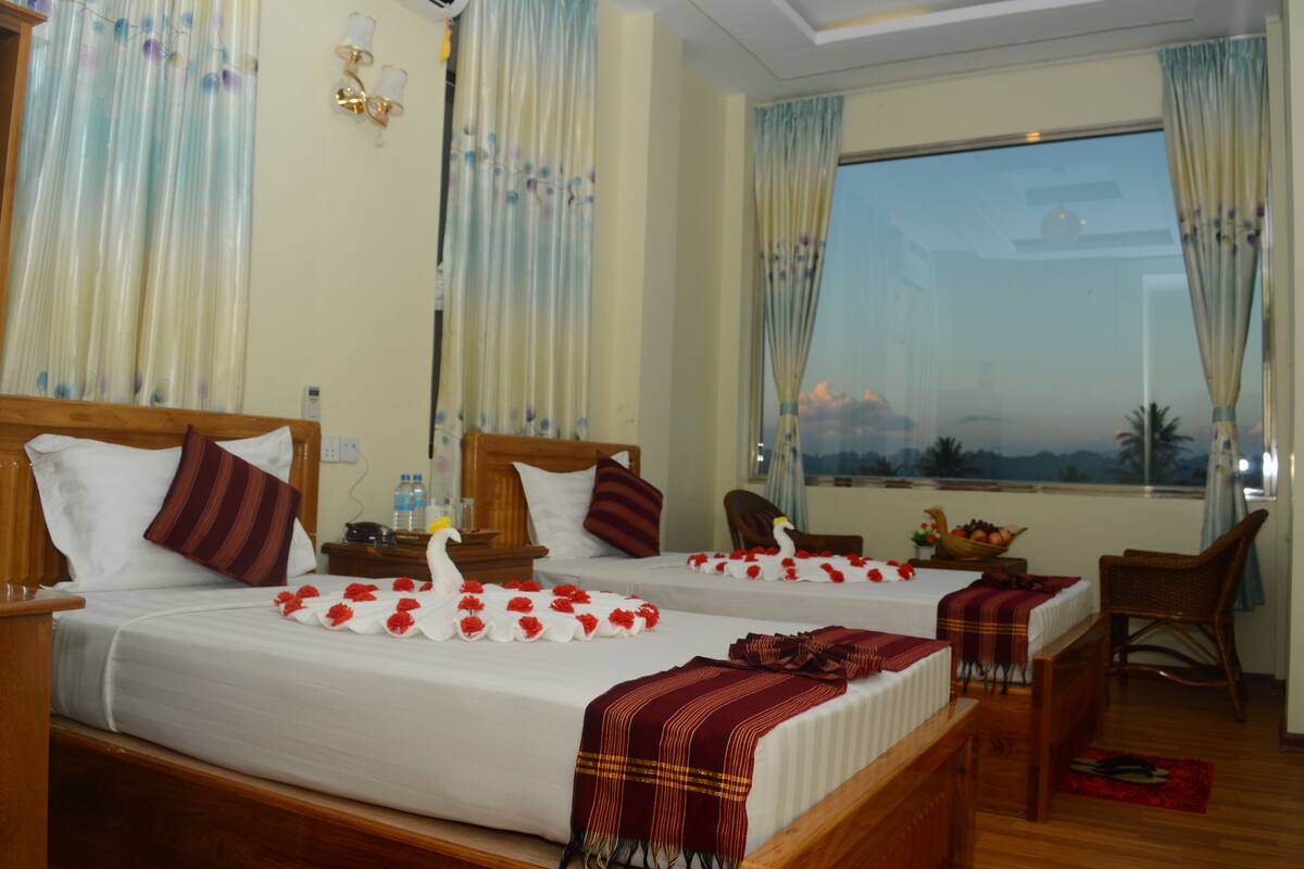Een hotelkamer met twee bedden, een zithoek en uitzicht op de zonsondergang.