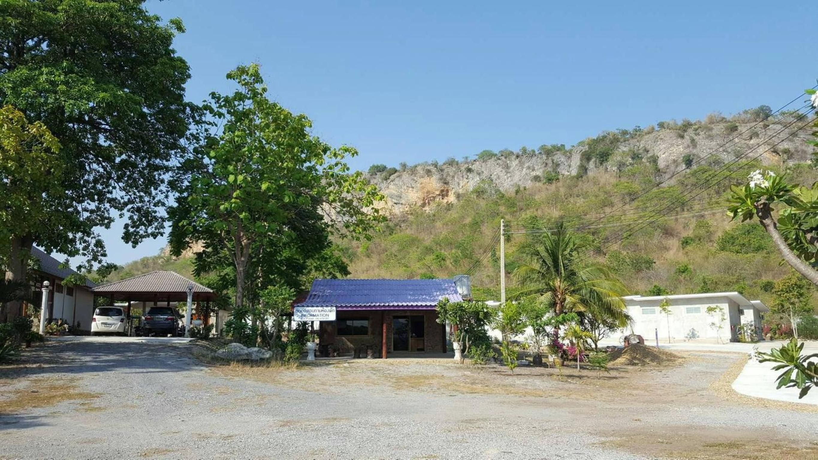 A building with a blue roof, surrounded by trees and a gravel driveway.