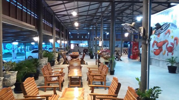 Een binnenzitgedeelte met houten tafels en stoelen, potplanten en een muurschildering van krabben.