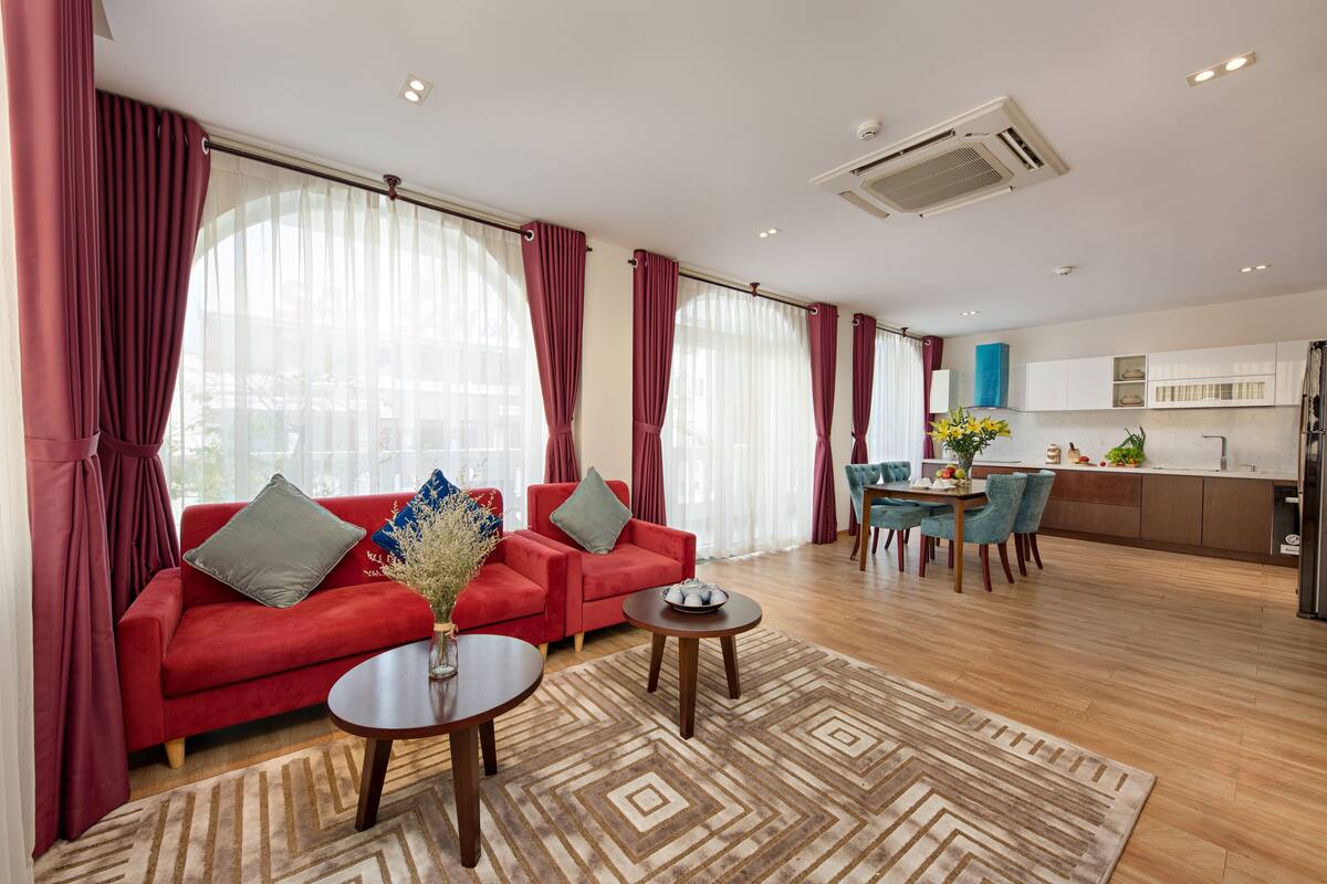 Una sala de estar moderna con un sofá rojo, una mesa de centro y una zona de comedor con una mesa y sillas azules.