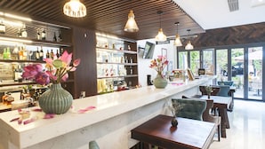 A bar area with a marble countertop, wooden ceiling, and pendant lighting. There are bar stools and a seating area with tables and chairs. - Sen Boutique Hotel (Da Nang)