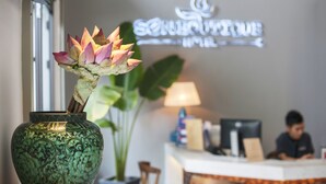 A reception desk with a neon sign, a vase with a plant, and a person working at the desk. - Sen Boutique Hotel (Da Nang)