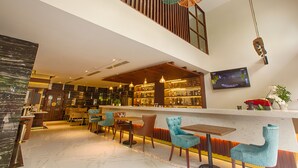 A modern bar area with a high ceiling, wooden slats, and hanging pendant lights. There are bar stools and a television mounted on the wall. - Sen Boutique Hotel (Da Nang)