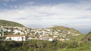 Un pueblo costero con edificios blancos, una carretera serpenteante y colinas al fondo.