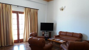 A living room with a brown leather sofa, two armchairs, a coffee table, and a flat-screen TV. - Hotel Boomerang (Valverde)