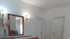 A room with a wooden desk, a mirror, a vase with branches, and two patterned armchairs. - Hotel Boomerang (Valverde)