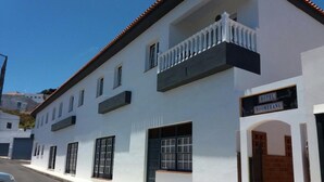 A white building with a balcony, a sign reading "HOTEL BOOMERANG," and a brick entrance. - Hotel Boomerang (Valverde)