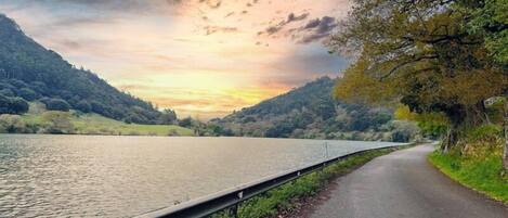 A road alongside a body of water with hills in the background.