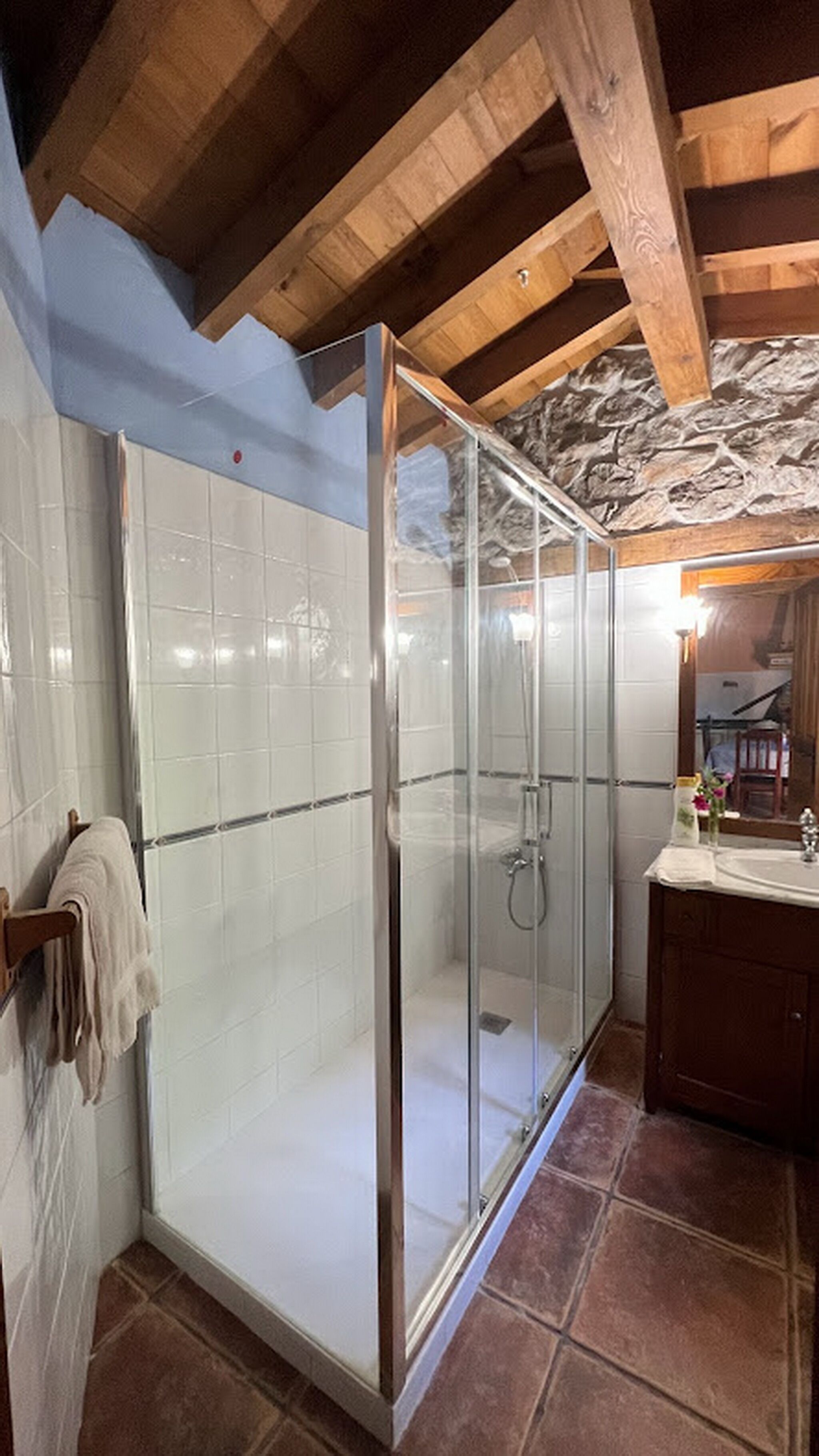 Una cabina doccia con pareti piastrellate e soffitto in legno.