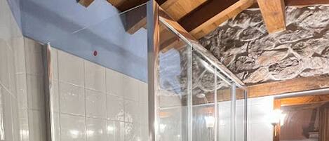 Una cabina doccia con pareti piastrellate e soffitto in legno.