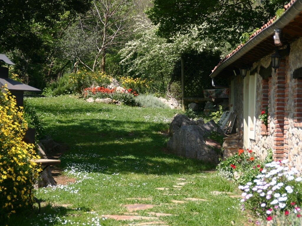 A garden with a stone pathway leading to a brick building with a sloped roof.