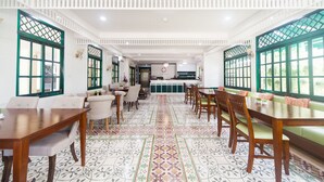 Un comedor espacioso con techos altos, baldosas de suelo estampadas y ventanas con marcos verdes.