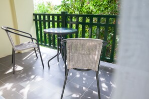 Un balcone con due poltrone in vimini e un tavolino rotondo.