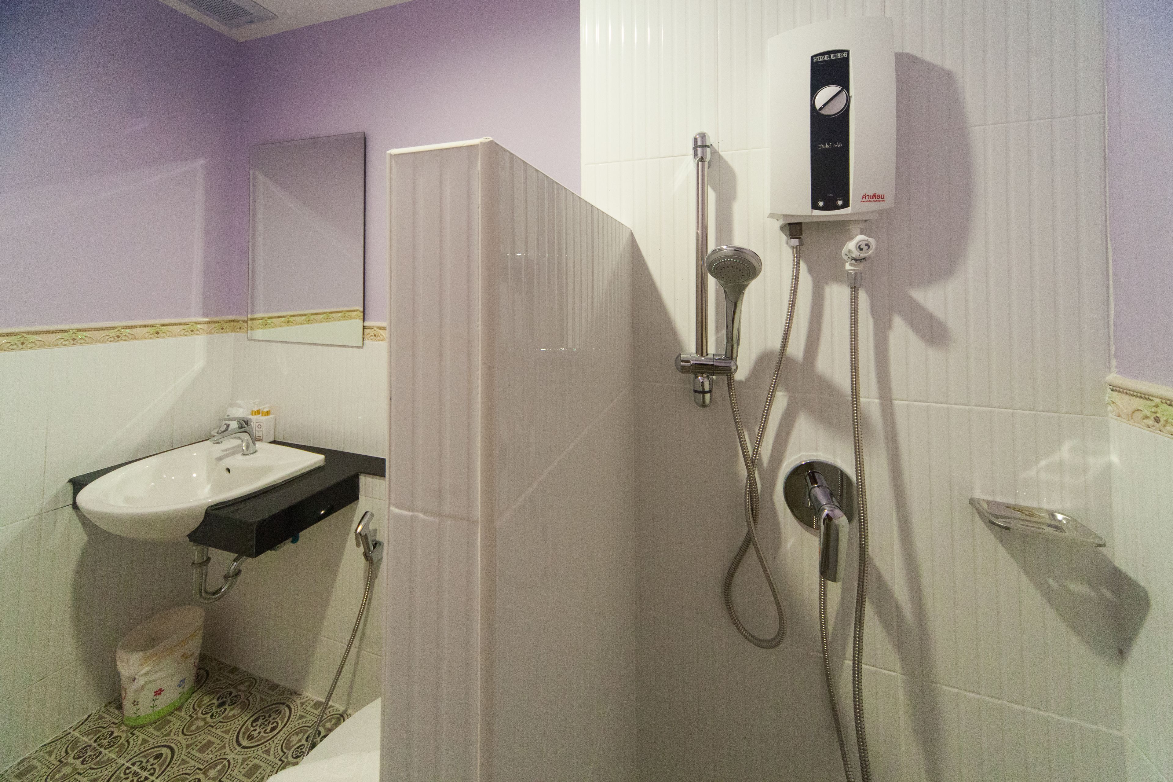 Un baño con lavamanos, espejo, ducha e inodoro.