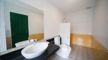 A bathroom with a large mirror, a white sink, a toilet, and a cabinet.