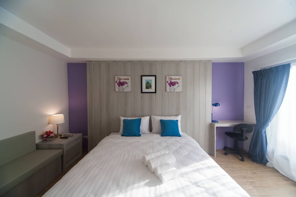 Una camera d'albergo ordinata con un letto, comodini, una scrivania e una sedia.