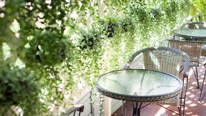 Un patio con mobiliario de mimbre y plantas colgantes.