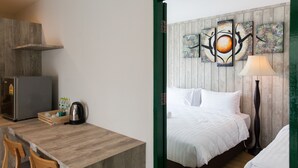 Habitación de hotel con un escritorio de madera, una cama con ropa de cama blanca, una obra de arte en la pared y una lámpara de pie.