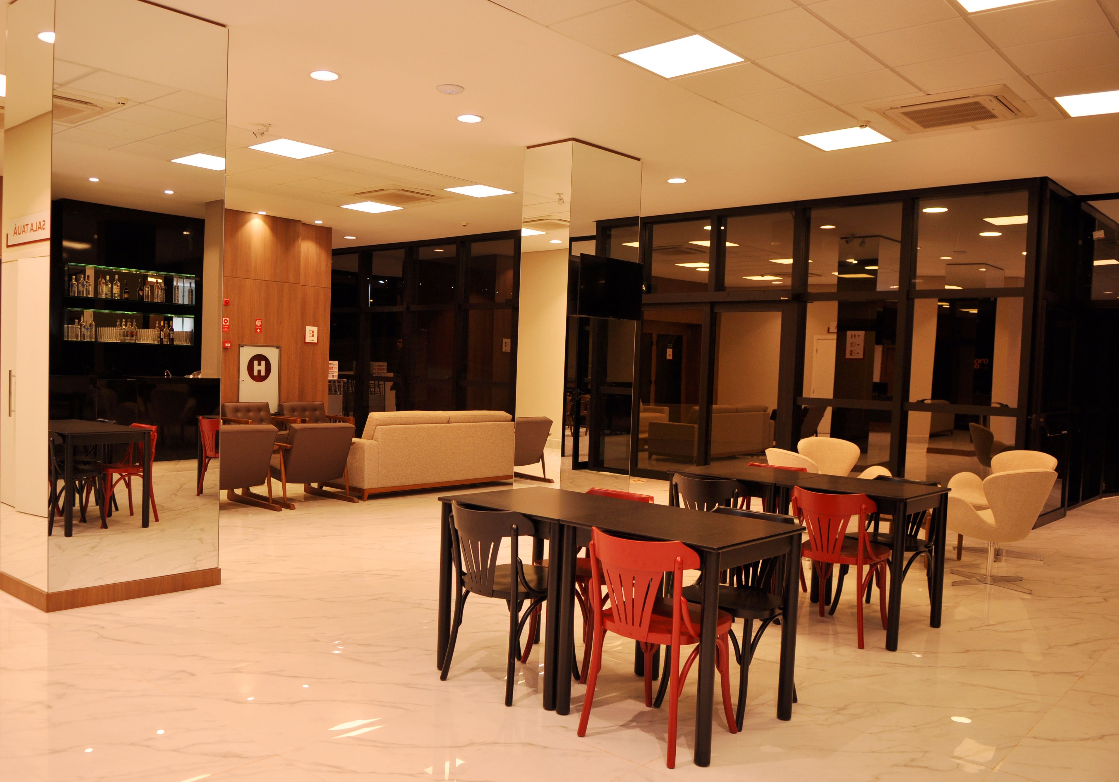 Een moderne hotellobby met een bar, zitgedeelte en een receptiebalie.