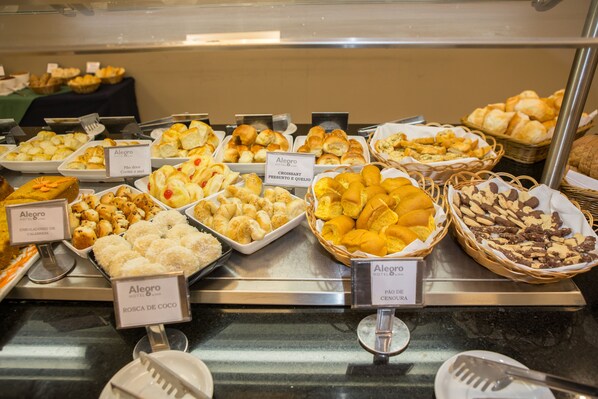 A buffet with various food items labeled, including croissants, pastries, and other baked goods. - Alegro Hotel (Jarinu)