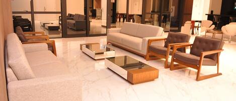 Un vestíbulo moderno con una zona de estar que incluye sofás y sillones, una mesa de centro de cristal y un suelo de mármol.