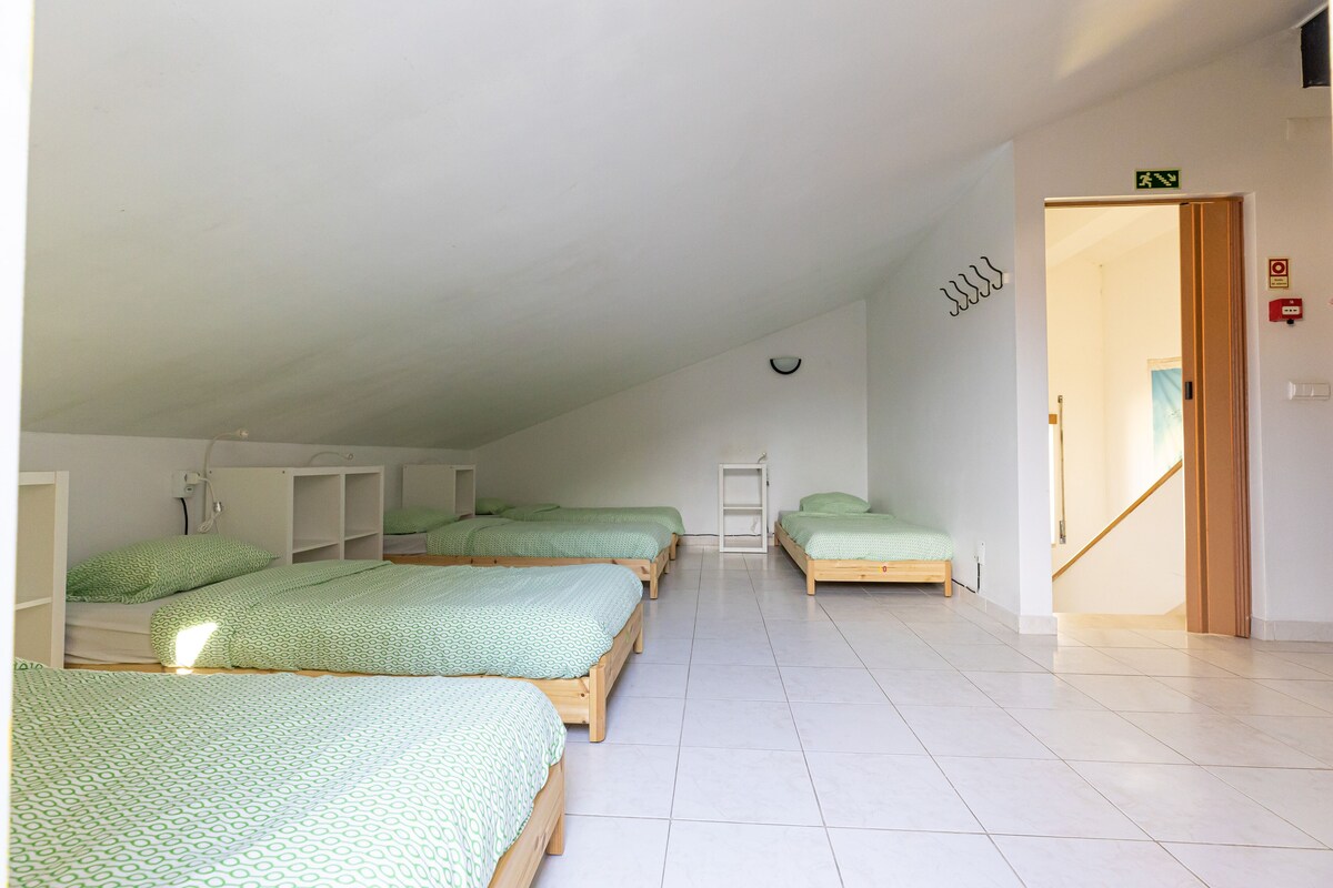 A dormitory room with four single beds, a white ceiling, and a tiled floor.