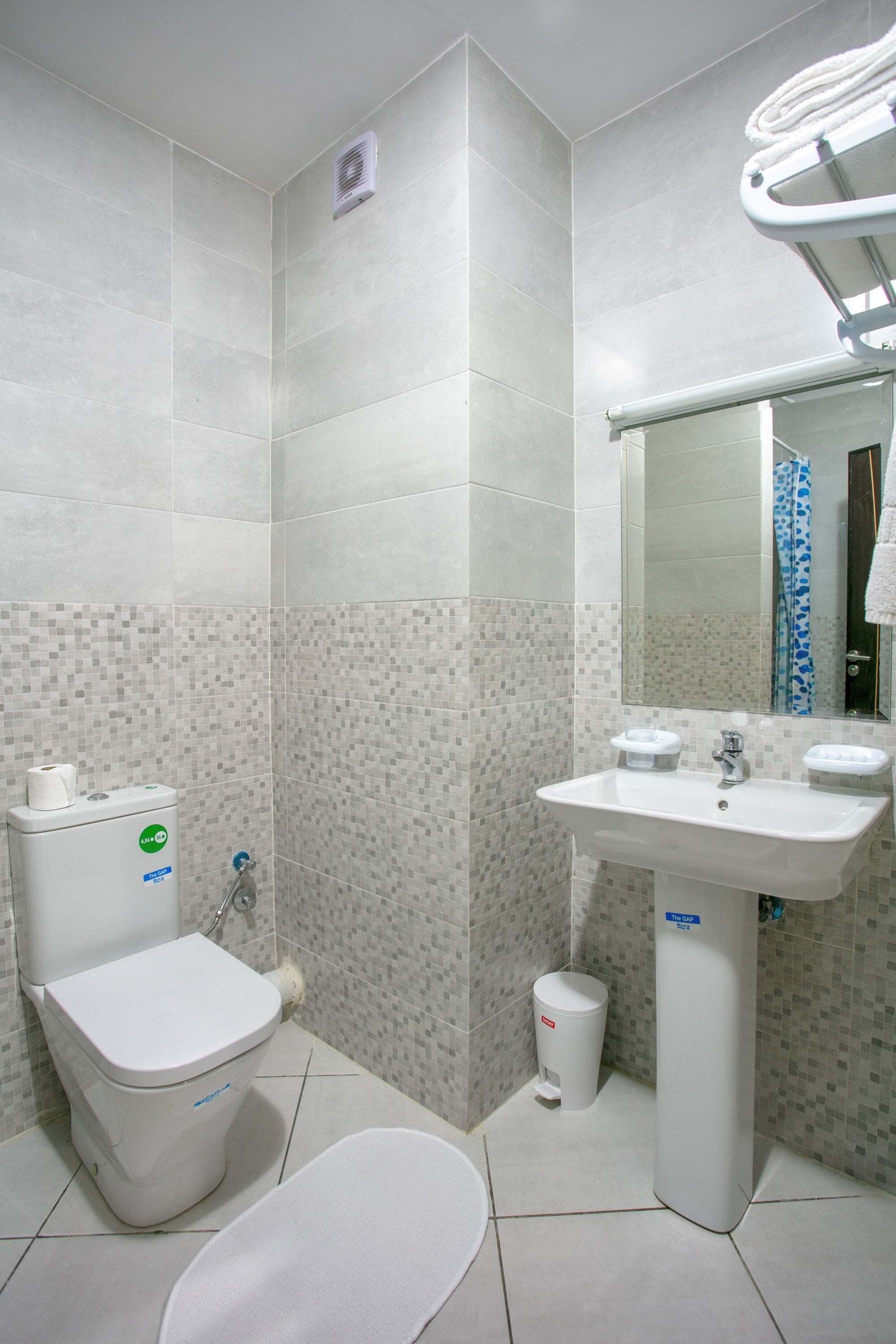 A bathroom with a toilet, sink, and mirror.