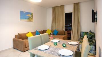 A dining area with a table set for four, a sofa, and a colorful couch.