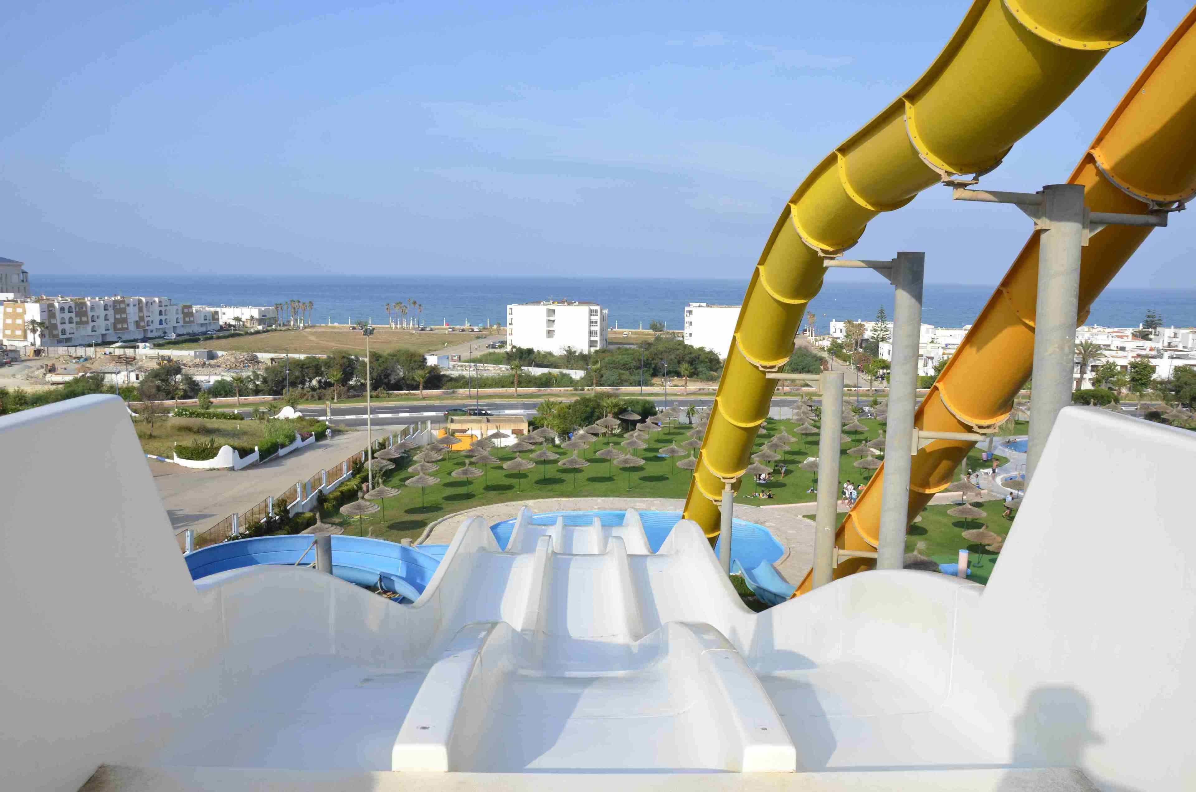 A water slide with a view of a coastal area, including buildings and a beach.